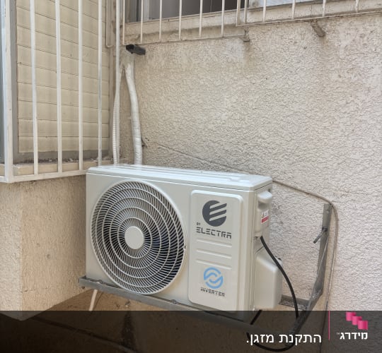 יחידת מזגן מותקנת על קיר חיצוני ליד חלון